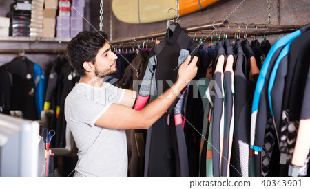 man holding and choosing suit for surfing in the shop 40343901