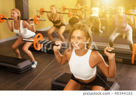 Girls exercising with barbell workout at fitness center 40344181