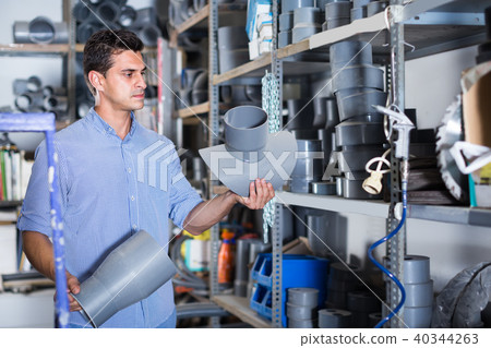 attentive male is choosing plastic trumpet in the plumbing department in store attentive male is choosing plastic trumpet in the plumbing department in store 40344263
