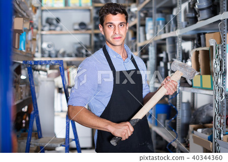 Portrait of craftsman in uniform who is standing with sledgehammer Portrait of craftsman in uniform who is standing with sledgehammer 40344360