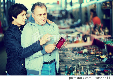 Adult man and woman are choosing jewelry box at the market of old things. Adult man and woman are choosing jewelry box at the market of old things. 40344611