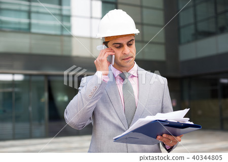 Businessman with documents talking on phone Businessman with documents talking on phone 40344805