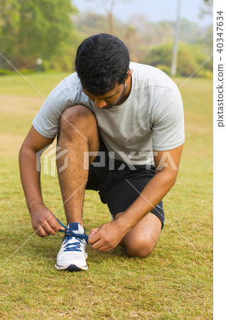 Young guy tying shoe laces & getting ready to run Young guy tying shoe laces & getting ready to run 40347634