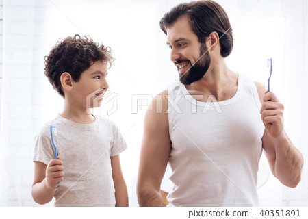 Adult father and son brush their together. 40351891