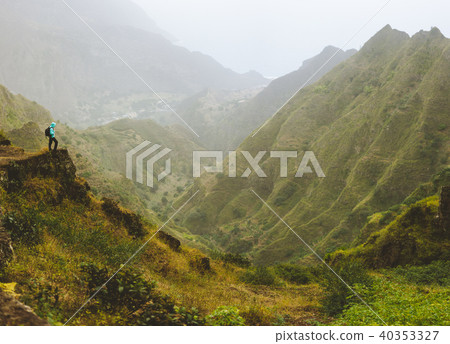 Hiker with backpack on the top of mountain edge. Rocky terrain in front of a incredible panorama Hiker with backpack on the top of mountain edge. Rocky terrain in front of a incredible panorama 40353327