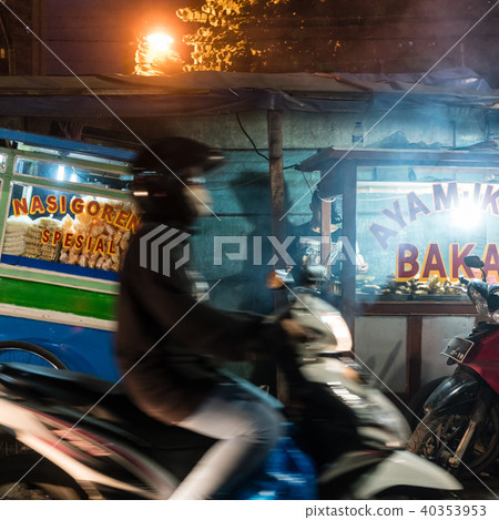 Man riding a scooter on a street with food stalls in a poor district of Jakarta Man riding a scooter on a street with food stalls in a poor district of Jakarta 40353953