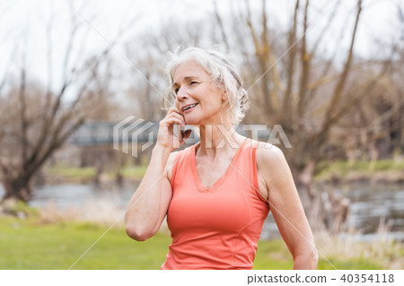 Senior woman in sport clothes receiving call on her mobile phone 40354118