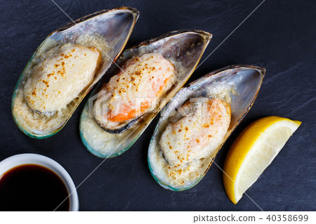 Baked shellfish mussels with soy sauce and lemon served on black 40358699