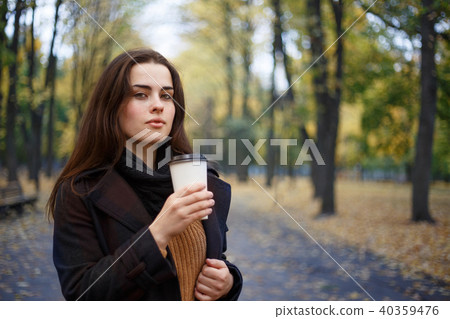 Young woman wearing knitted sweater and coat walking in the autu Young woman wearing knitted sweater and coat walking in the autu 40359476