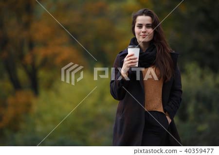 Young stylish woman wearing knitted sweater and coat walking in  40359477