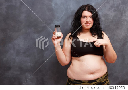 Overweight fat woman pointing on a bottle of slimming pills. Wei 40359953