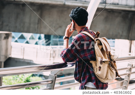 Casual Young asian man with backpack talking phone Casual Young asian man with backpack talking phone 40361602