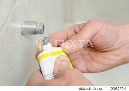 Plumber putting a paste sealant. Plumber putting a paste sealant. 40369734
