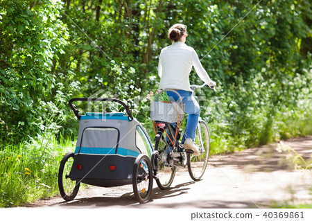 Mother on bicycle with baby bike trailer in park 40369861