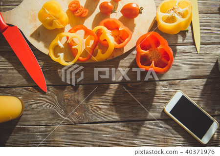 Wooden surface with sliced vegies and cellphone Wooden surface with sliced vegies and cellphone 40371976
