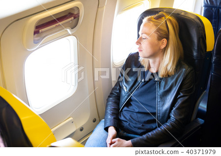 Tired blonde casual caucasian lady napping on seat while traveling by airplane. 40371979
