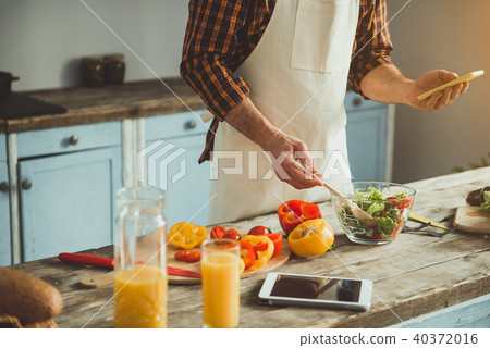 Male person cooking with phone in hand Male person cooking with phone in hand 40372016