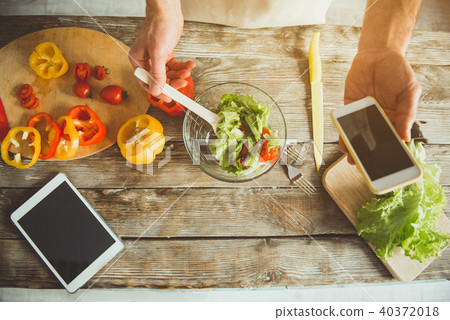 Man cooking with cellphone in arm Man cooking with cellphone in arm 40372018