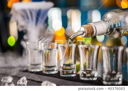 Barman pouring hard spirit into glasses 40376083