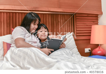 Young mother reading a book to her daughter. 40378016