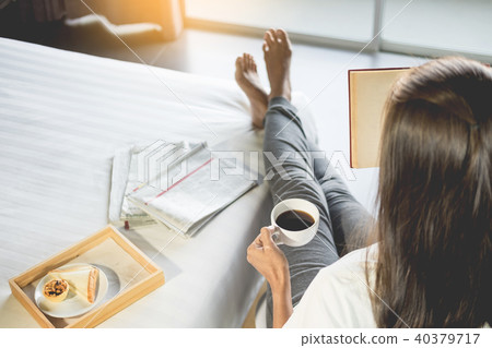 Woman reading book or newspaper and drinking coffee breakfast on Woman reading book or newspaper and drinking coffee breakfast on 40379717