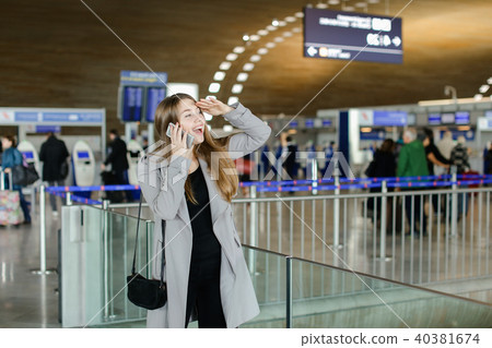 Caucasian woman talking by smartphone and looking for friend at aiport. 40381674