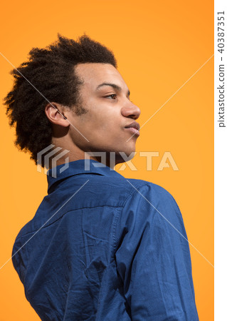 Beautiful male half-length portrait isolated on orange studio backgroud. The young emotional Beautiful male half-length portrait isolated on orange studio backgroud. The young emotional 40387351
