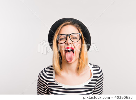 Portrait of a young beautiful woman in studio, sticking out tongue. Portrait of a young beautiful woman in studio, sticking out tongue. 40390683