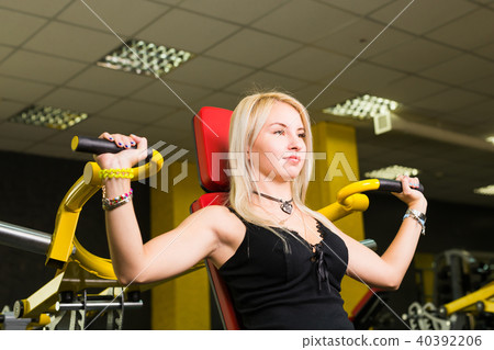 Beautiful woman at the gym exercising on a machine. Beautiful woman at the gym exercising on a machine. 40392206