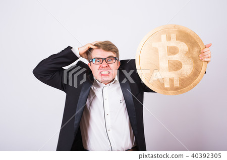 Portrait of a screaming businessman holds big golden bitcoin in his arms. Man in panic of 40392305