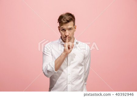 The young man whispering a secret behind her hand over pink background The young man whispering a secret behind her hand over pink background 40392946