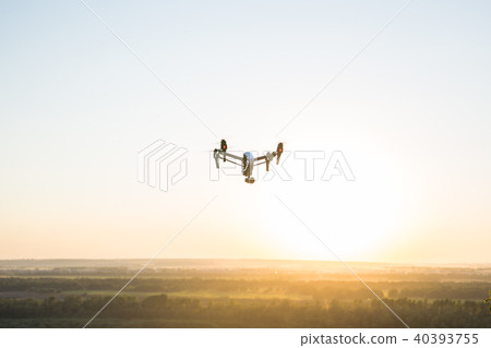 silhouette of drone, quadrocopter with photo camera flying in the sky. 40393755