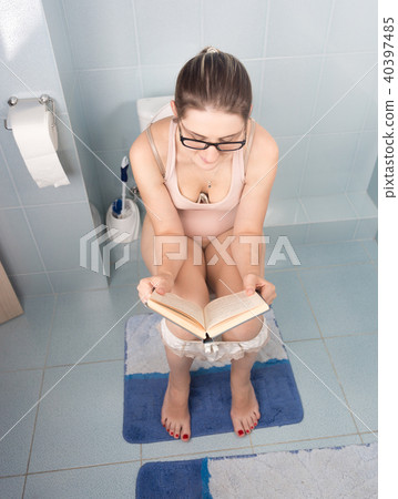 Young brunette woman studying and reading book while using toilet 40397485