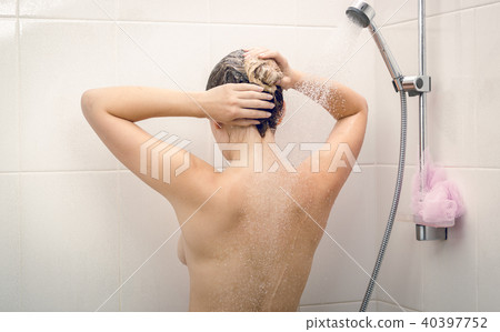 Toned rear view image of beautiful young woman washing off shampoo from hair 40397752