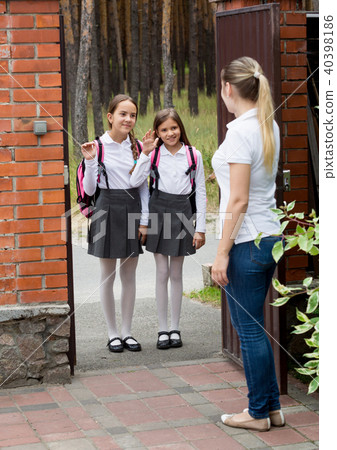 Two teenage girls waving hands to mother before going to school 40398186