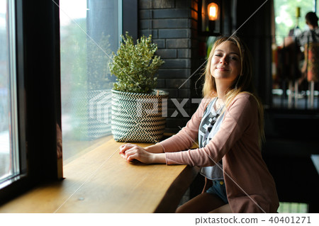 Young woman sitting near window at cafe and dreaming. Young woman sitting near window at cafe and dreaming. 40401271