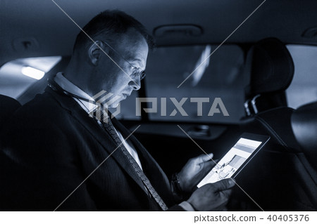 Businessman with a digital tablet sitting in the back seat of a car 40405376