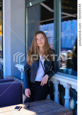 Happy female person standing near window of cafe with smartphone on table. Happy female person standing near window of cafe with smartphone on table. 40409544
