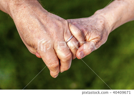 Senior couple holding hands while sitting together in the garden 40409671