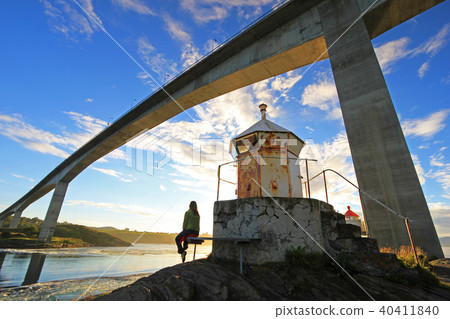 Woman sitting under the bridge at the fjord of the whirlpools of the maelstrom of Saltstraumen Woman sitting under the bridge at the fjord of the whirlpools of the maelstrom of Saltstraumen 40411840