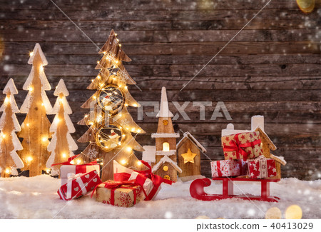 Holidays background with illuminated Christmas tree, sledge with gifts and wooden village. Holidays background with illuminated Christmas tree, sledge with gifts and wooden village. 40413029