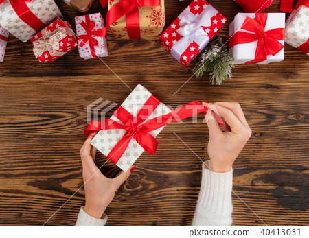 Woman packing Christmas presents on wooden table background Woman packing Christmas presents on wooden table background 40413031