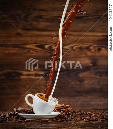 Splashing liquid of coffee and milk into white cup on wooden table Splashing liquid of coffee and milk into white cup on wooden table 40413297