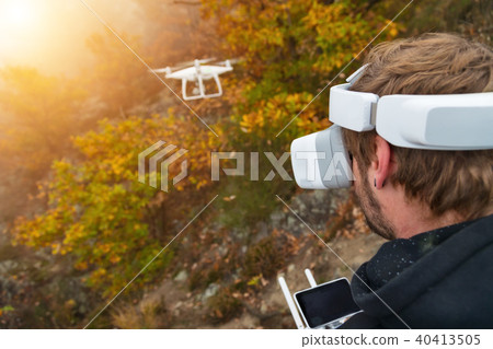Young man handling drone, using virtual reality glasses. Young man handling drone, using virtual reality glasses. 40413505