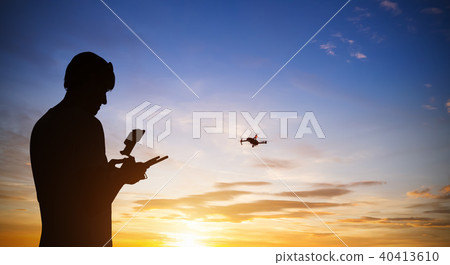 Drone pilot with quadrocopter. Silhouette against the sunset sky Drone pilot with quadrocopter. Silhouette against the sunset sky 40413610