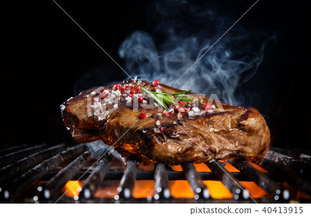 Beef steak on the grill grate, flames on background Beef steak on the grill grate, flames on background 40413915