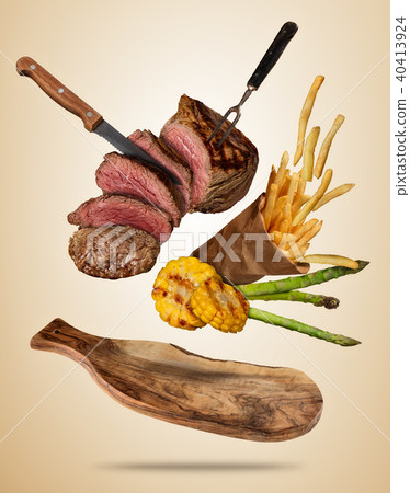 Flying beef steaks with grilled vegetable and french fries served on wooden cutting board. Flying beef steaks with grilled vegetable and french fries served on wooden cutting board. 40413924
