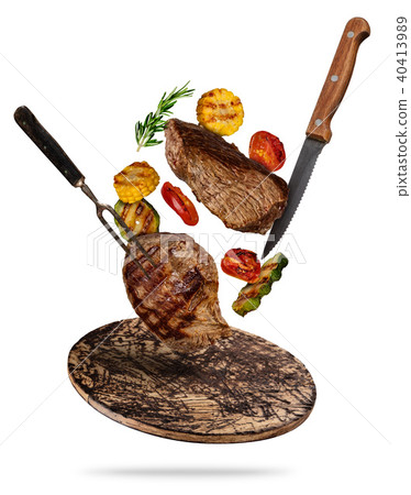 Flying beef steaks with grilled vegetable served on wooden cutting board. 40413989