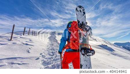 Snowboarder walking on snowshoes in powder snow. 40414941
