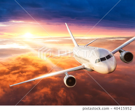 Airplane flying above clouds in dramatic sunset 40415952